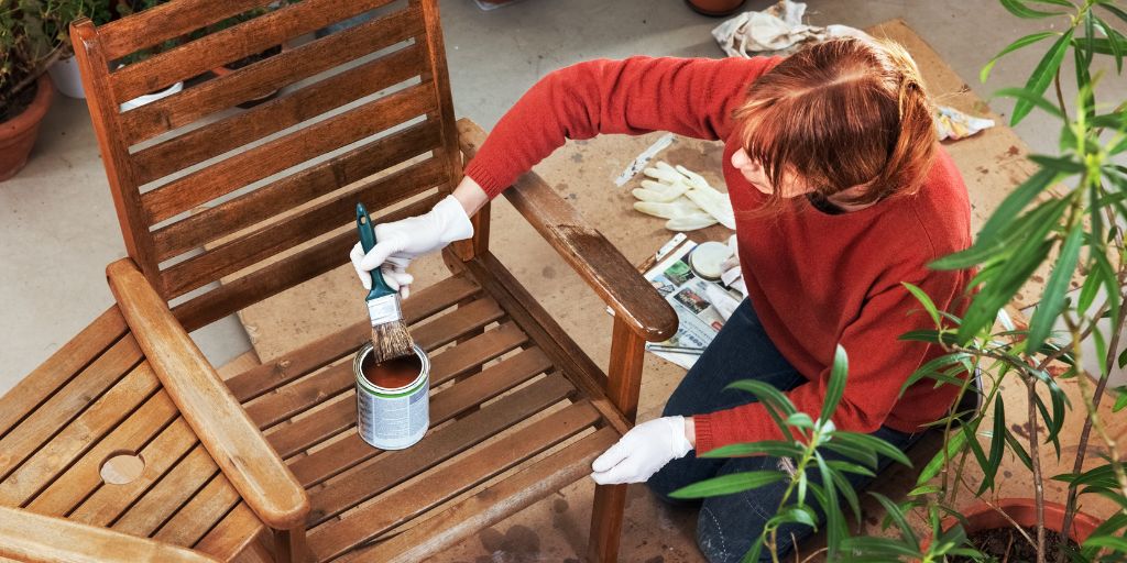 Woman painting wooden garden furniture with a protective coating