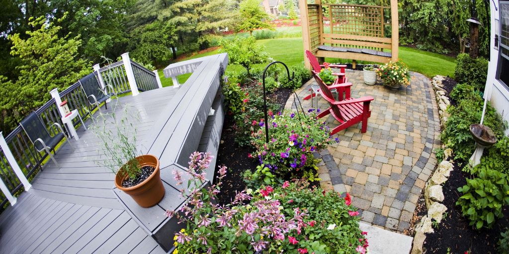 A small cottage garden with light grey composite decking and bright flowers